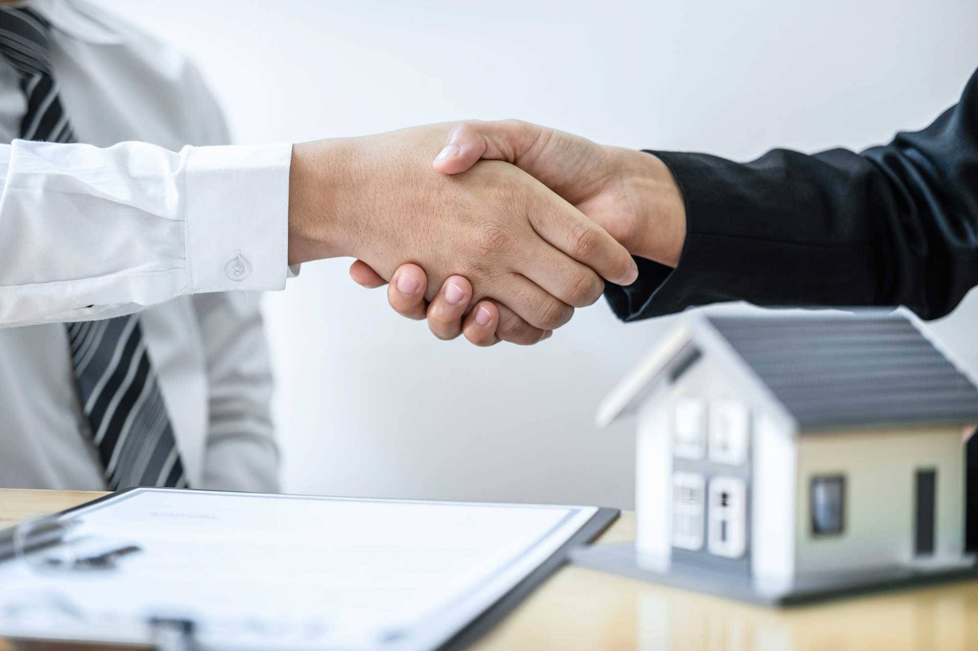 Real estate agent are shaking hands after good deal and giving house